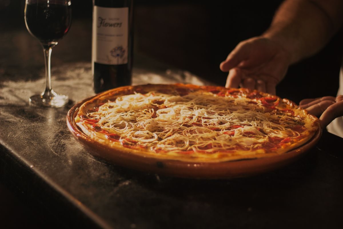 Fresh pizza on the table with a glass of wine
